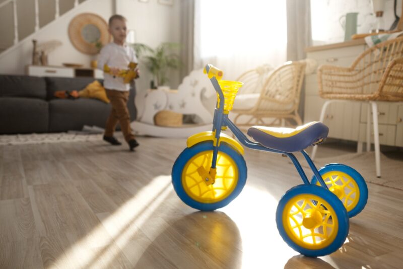pelne-ujecie-szczesliwego-dziecka-z-trojkolowym-rowerem-w-domu (1)